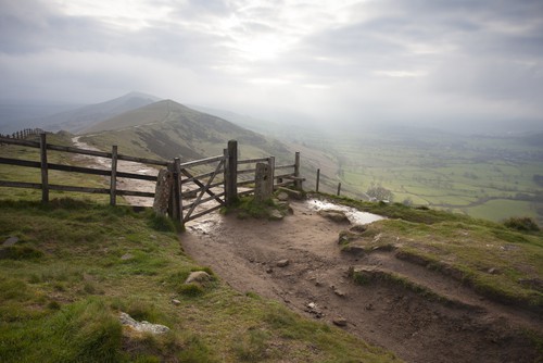 a path on a hill with mist in the distance